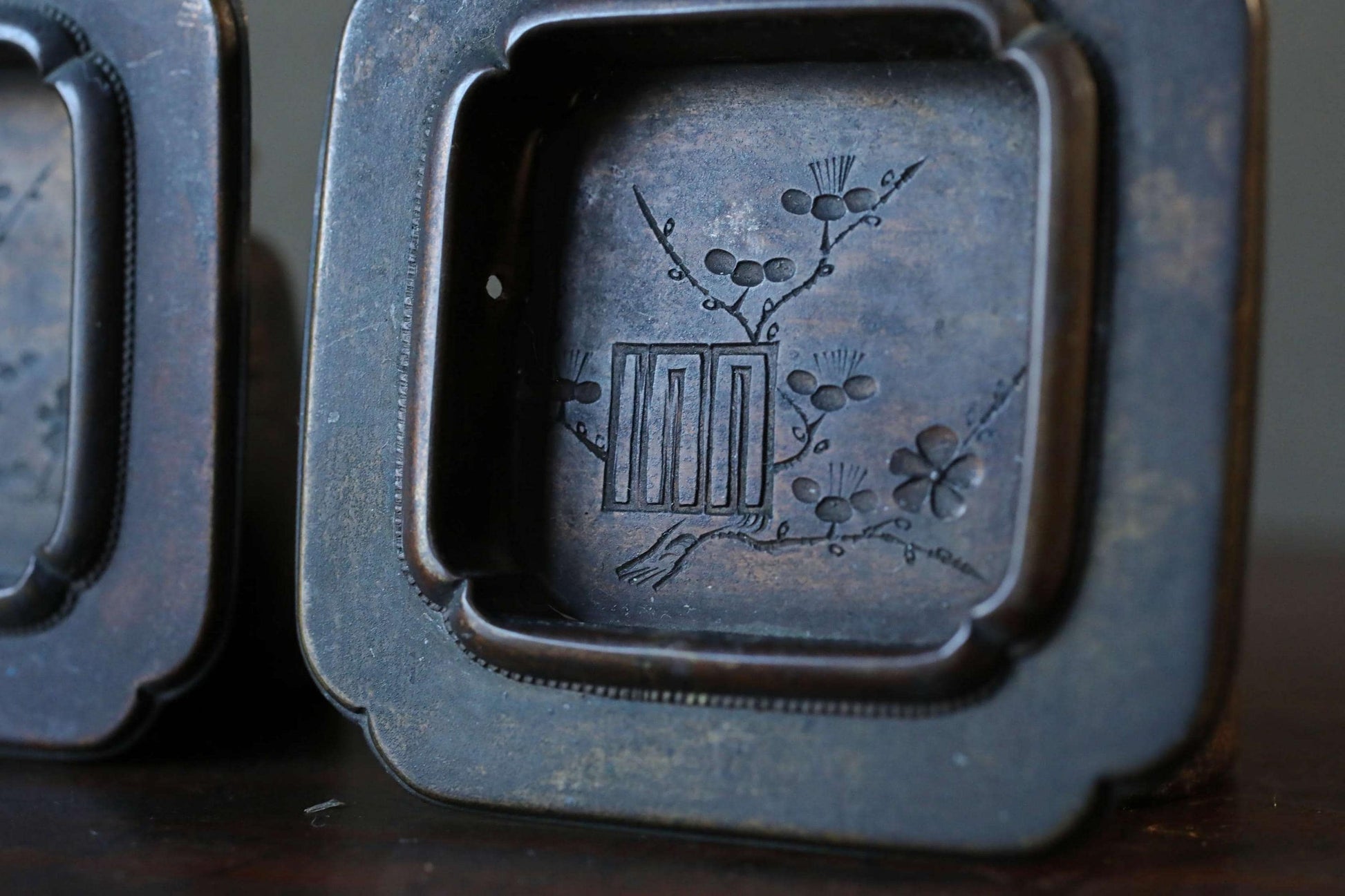 a close-up view of a dark metal object, possibly a piece of art or a decorative item, with a floral design on it.