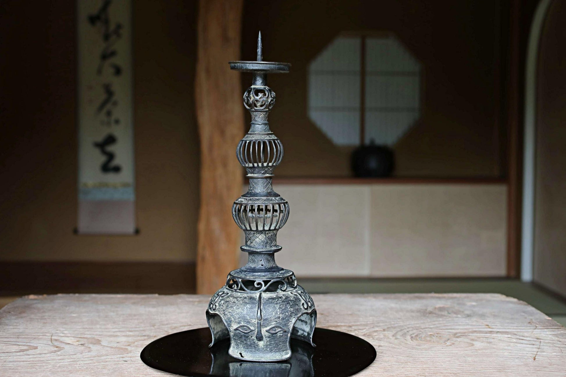 a decorative metal candlestick with an ornate, multi-tiered design, placed on a wooden surface.