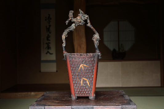 a traditional Japanese basket with a wooden handle and a decorative design on the front.