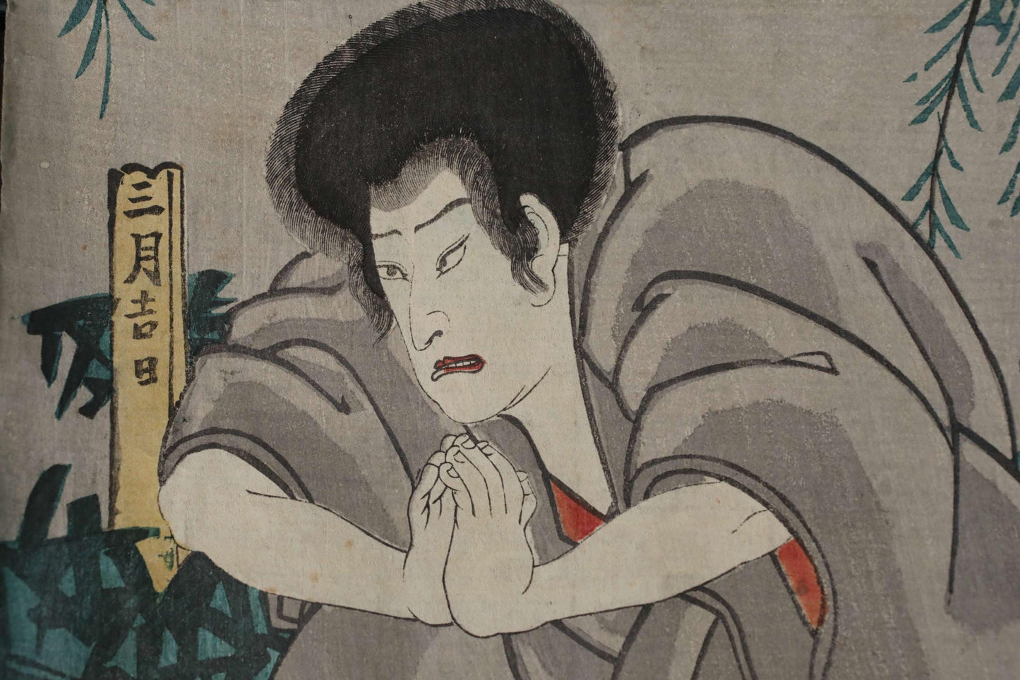 a man with a serious expression, wearing a gray robe and sitting in a contemplative pose.