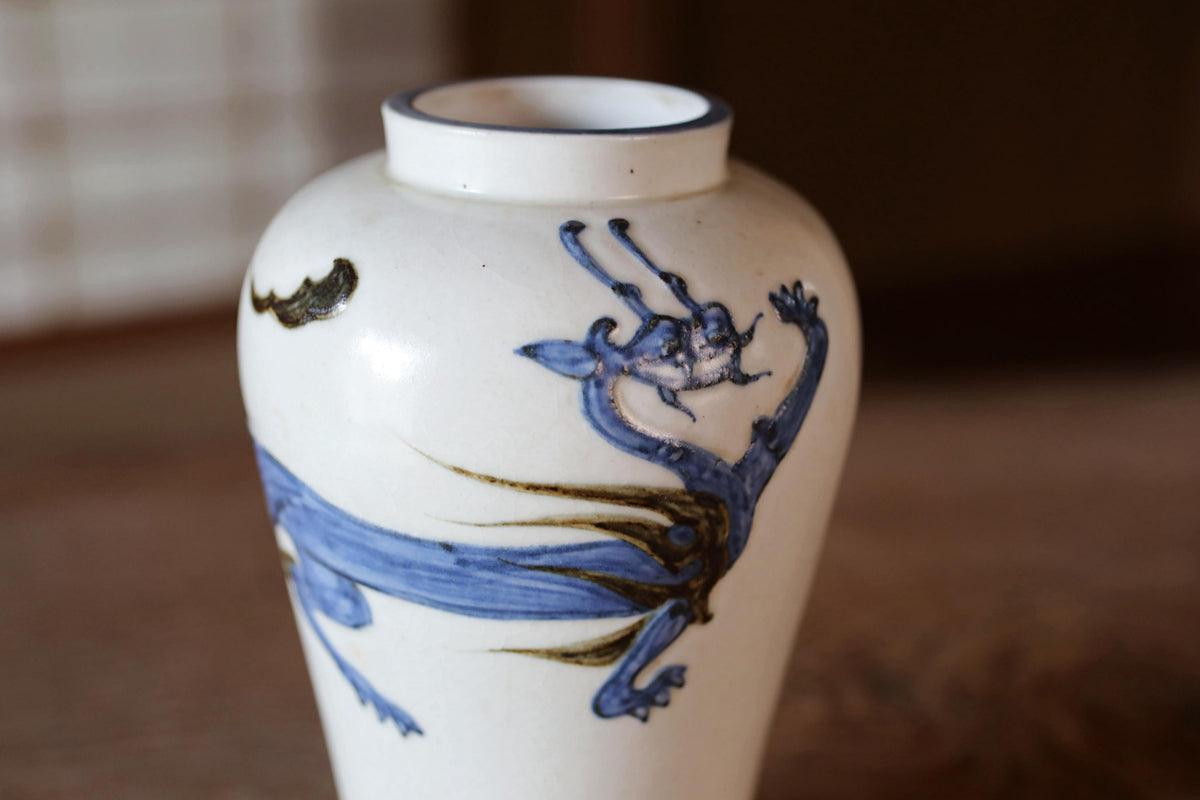 A white ceramic vase with a blue dragon design on it.