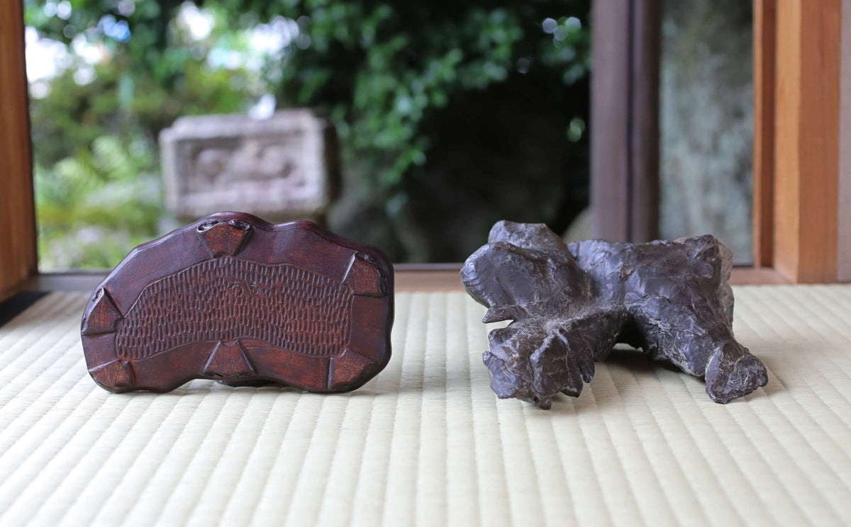two wooden objects, one larger and one smaller, placed on a white surface.