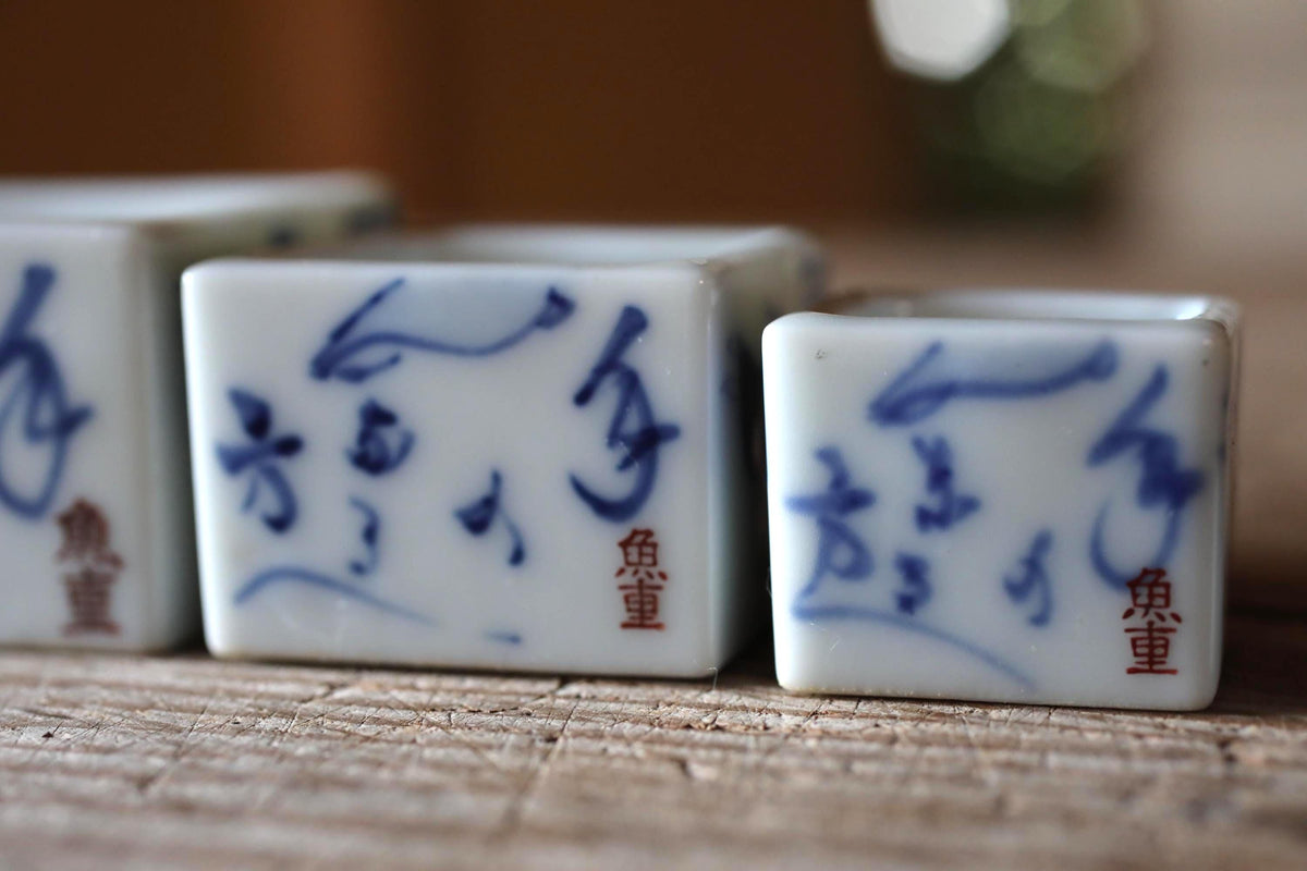 three square ceramic containers with blue designs and Chinese characters on them.