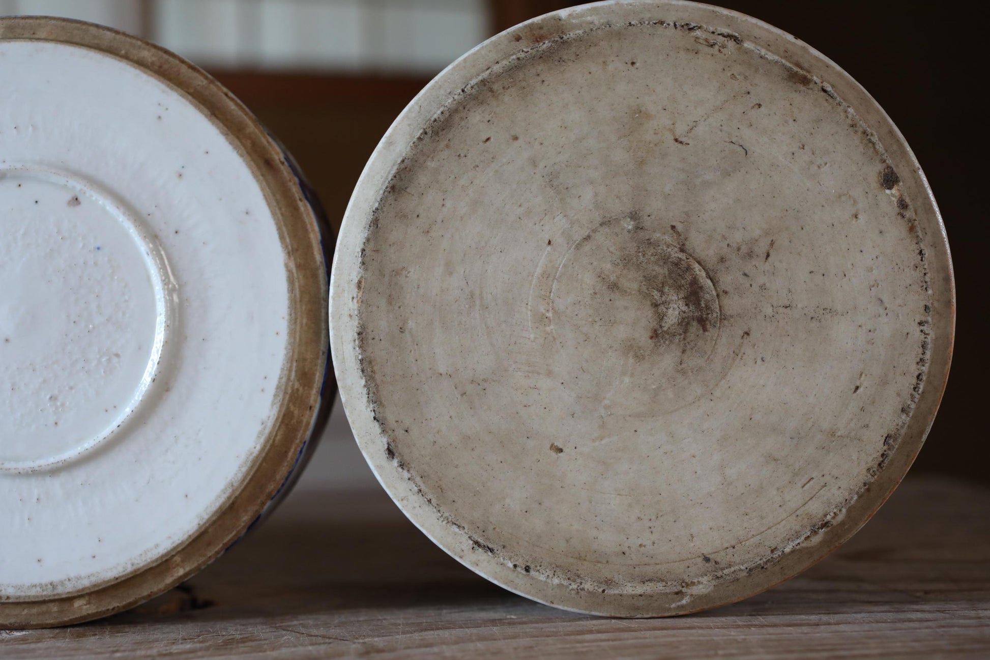 Two old, dirty ceramic bowls or containers with a circular shape and a white interior.