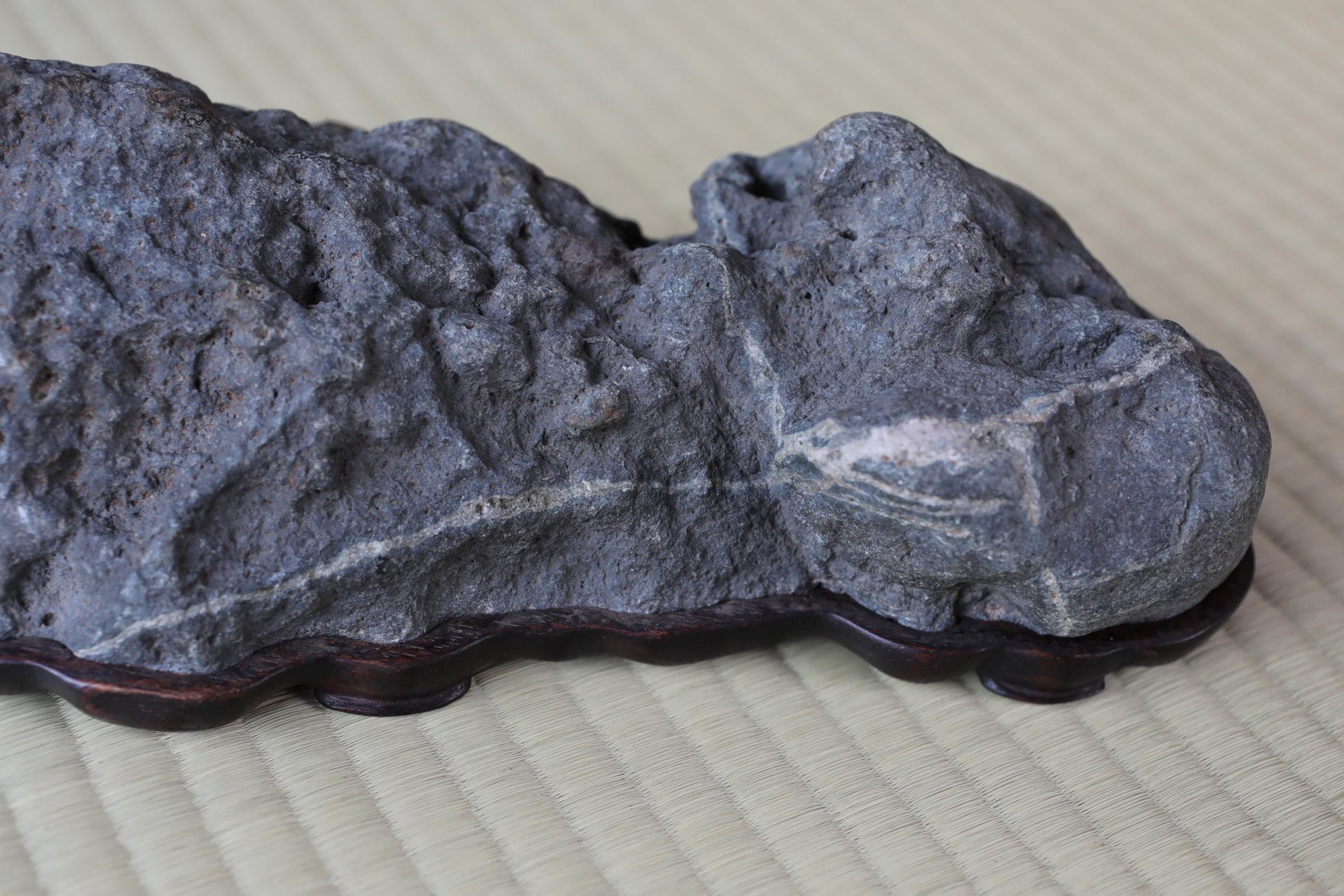 a close-up view of a large, gray rock with a carved design on its surface, resting on a wooden base.