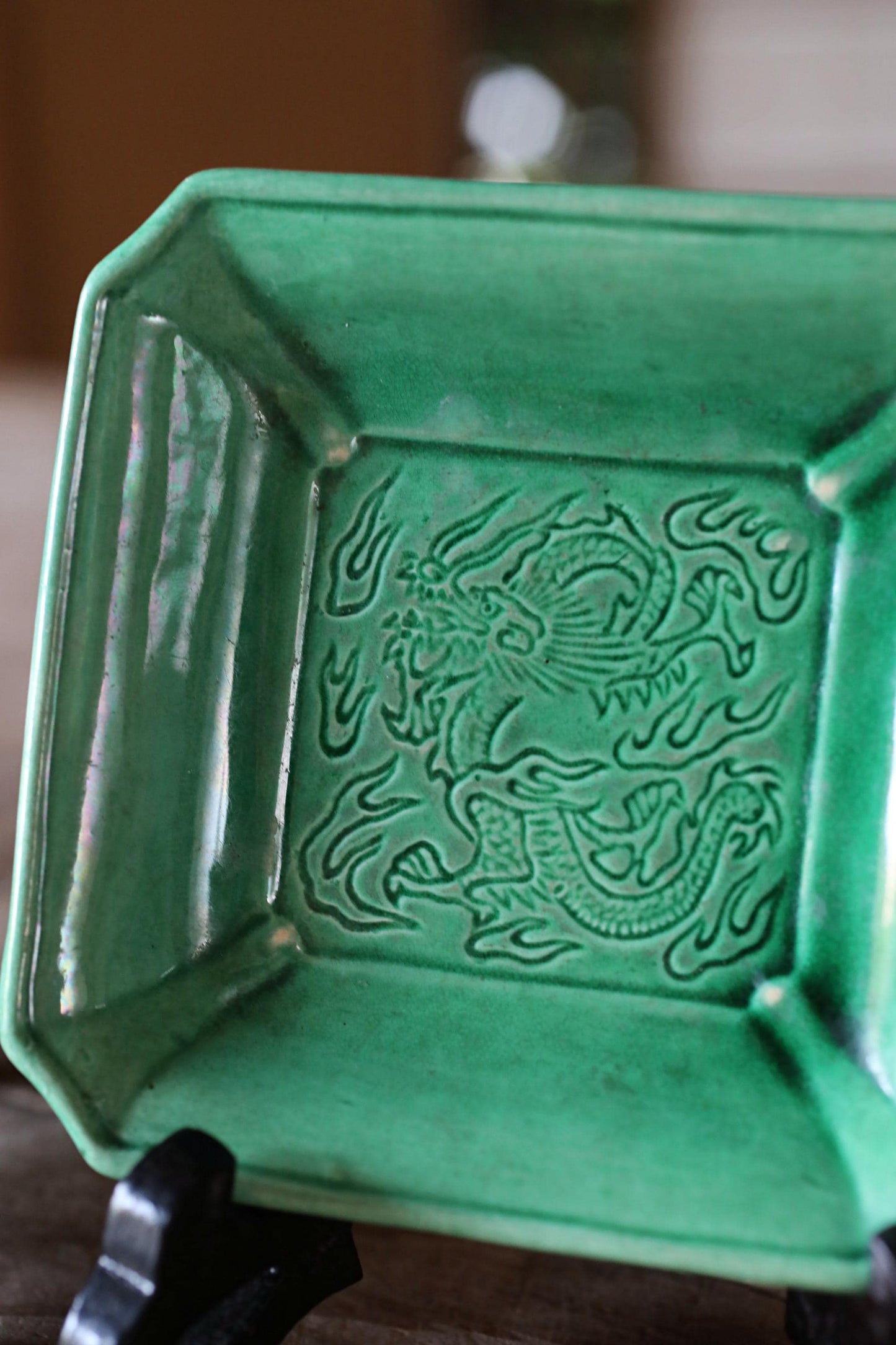 A green ceramic bowl with an intricate dragon design on it.