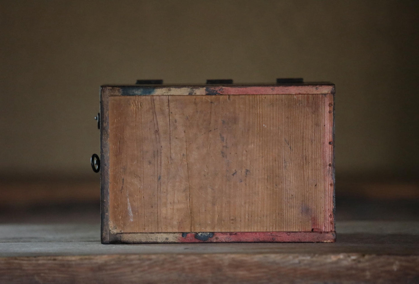 a wooden box with a weathered, aged appearance, sitting on a wooden surface.