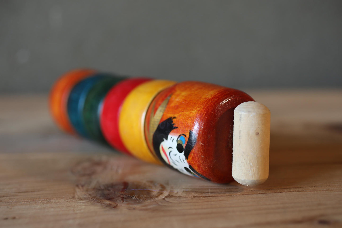 A colorful wooden toy with a cartoon character on it, sitting on a wooden surface.