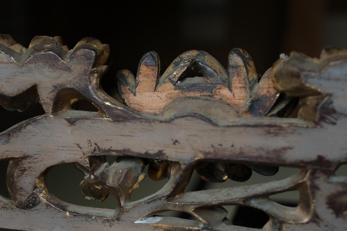 a close-up view of a wooden carving with intricate designs and patterns, including floral and animal motifs. The wood appears to be weathered and aged, giving it a rustic and antique appearance.