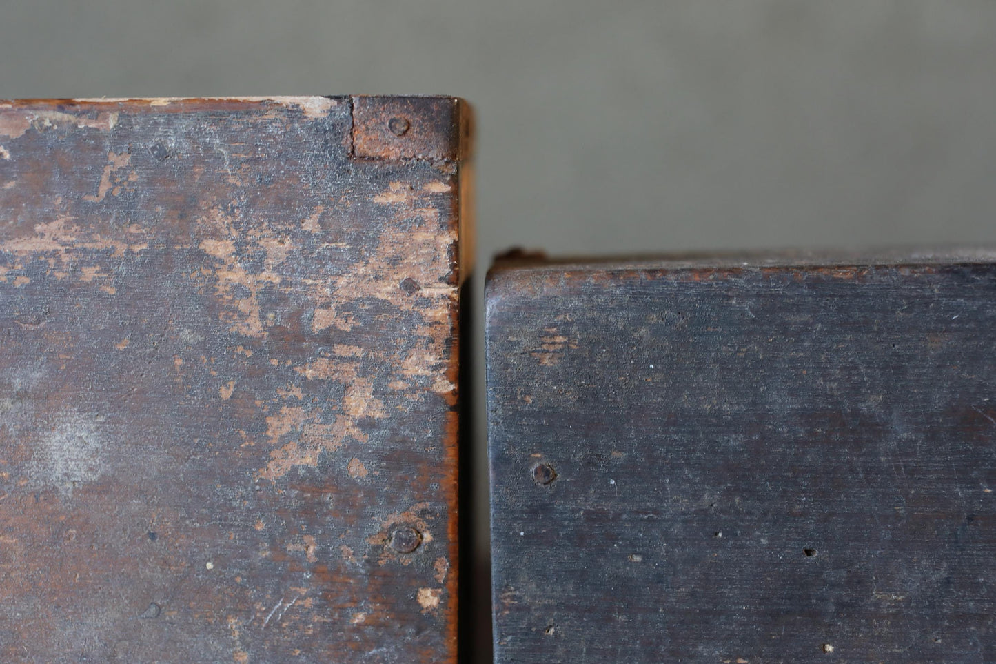 two old, weathered wooden planks or blocks, one with a rusty, peeling surface and the other with a smoother, darker finish.