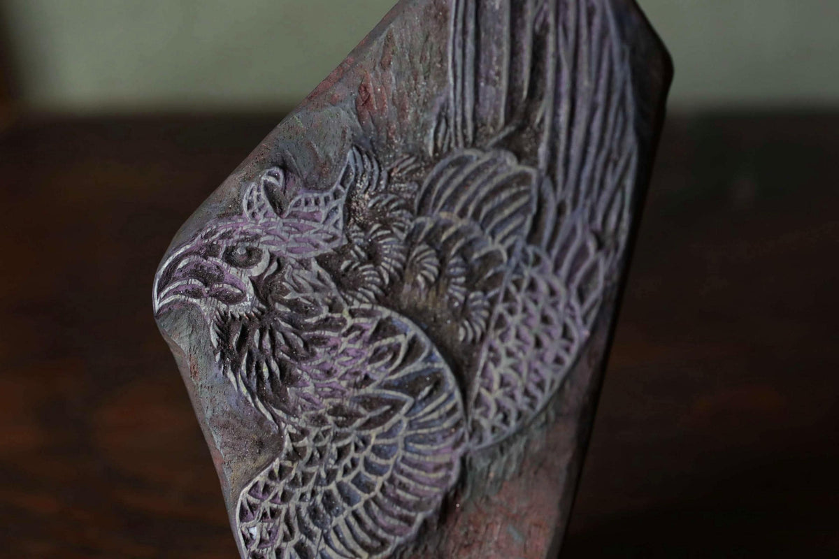 a close-up view of a detailed carving of a bird on a piece of wood.