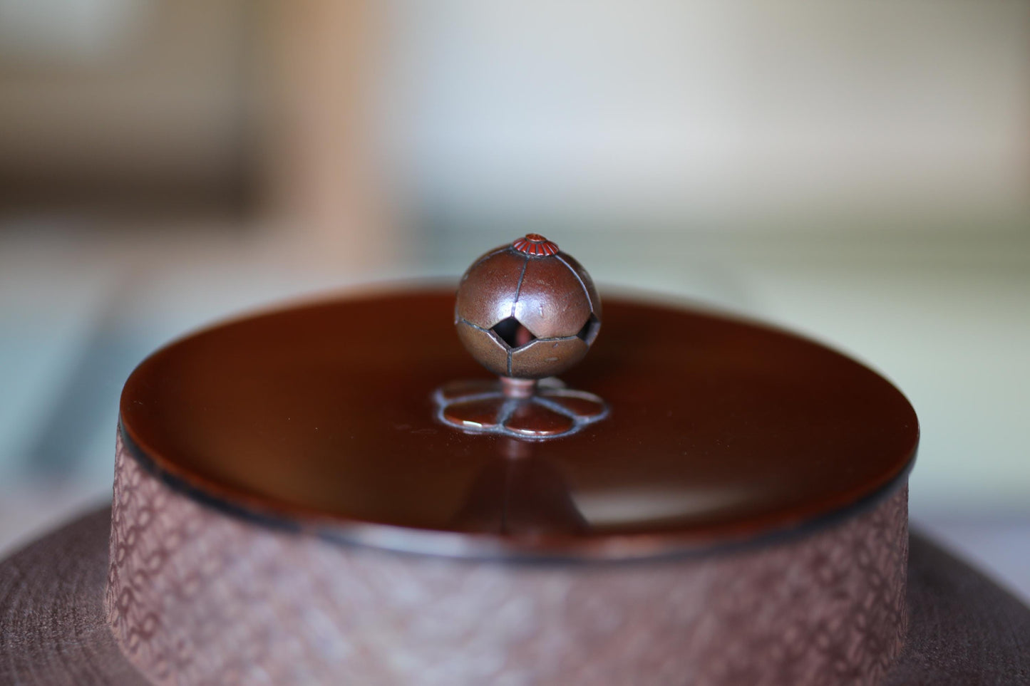A close-up image of a round, brown object with a metallic, textured surface, sitting on top of a round, brown object with a similar textured surface.