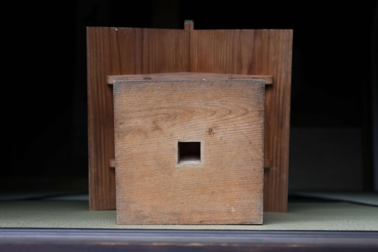 a wooden structure with a square cutout in the center, likely a piece of furniture or a decorative element.