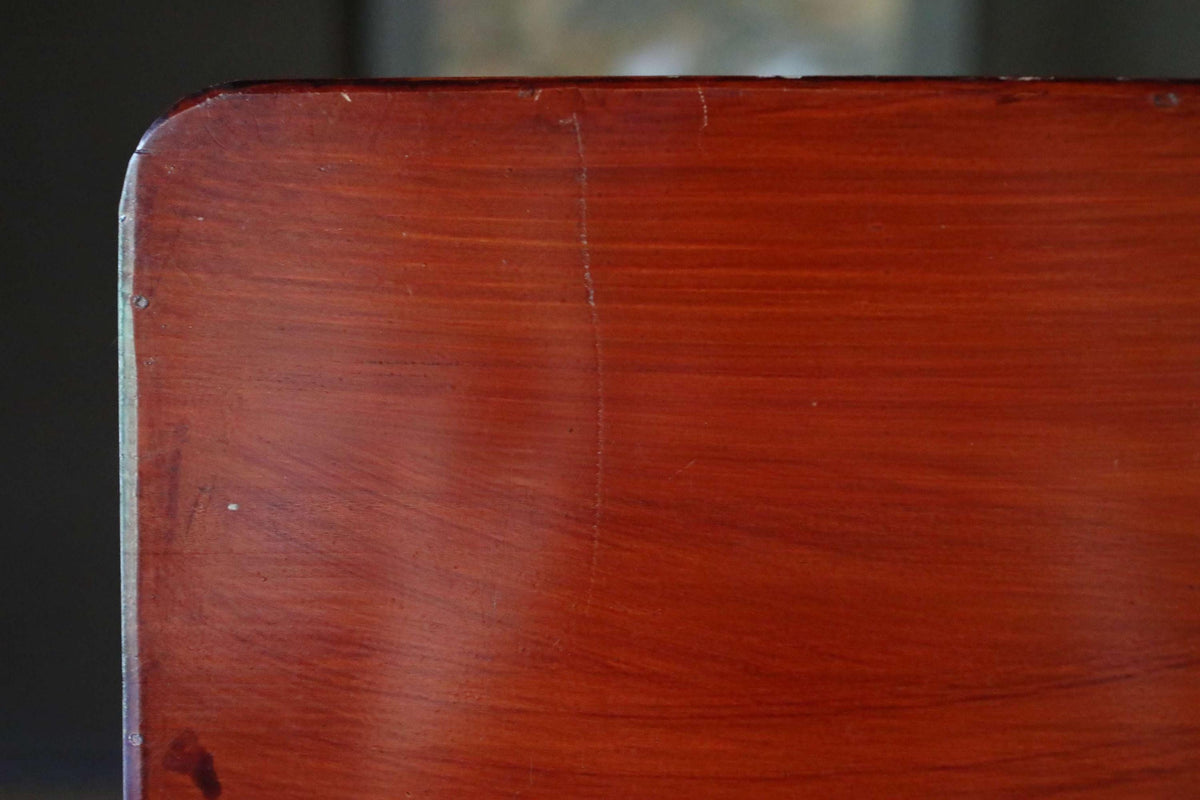 a close-up view of a wooden surface, possibly a table or a piece of furniture, with a rich, warm brown color and visible grain patterns.