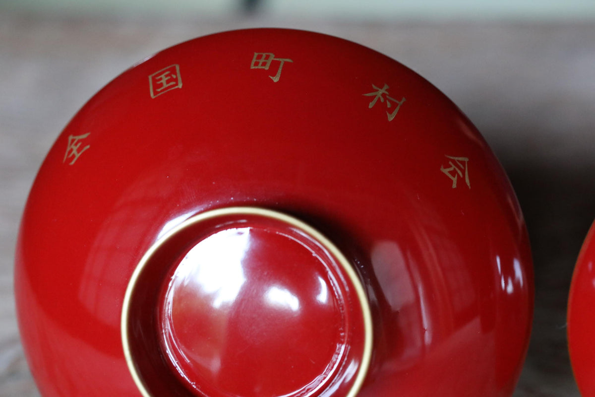 A close-up view of a red bowl with Chinese characters on it.