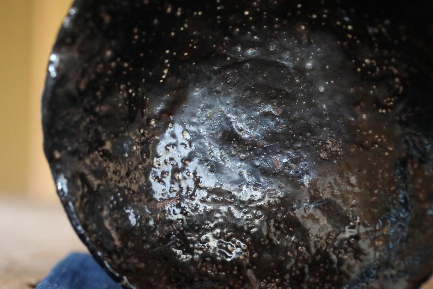 A close-up view of a black, textured surface with small holes or specks scattered across it.