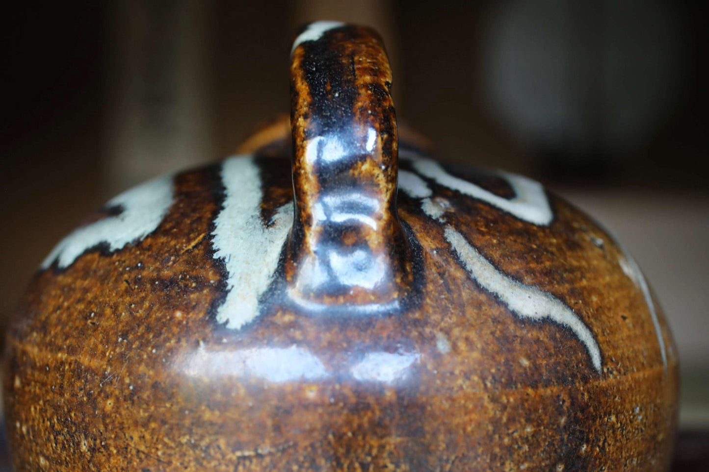 A close-up image of a brown and white ceramic jug with a handle, featuring a distinctive design.