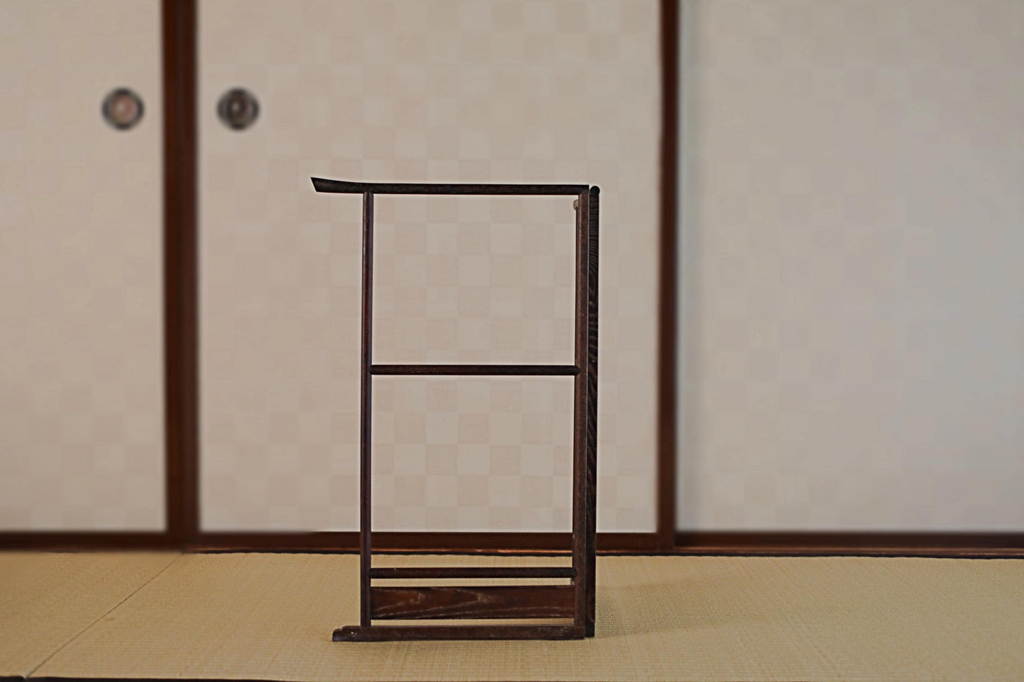 a wooden podium or podium with a curved top, standing on a tatami mat in a room with sliding doors.