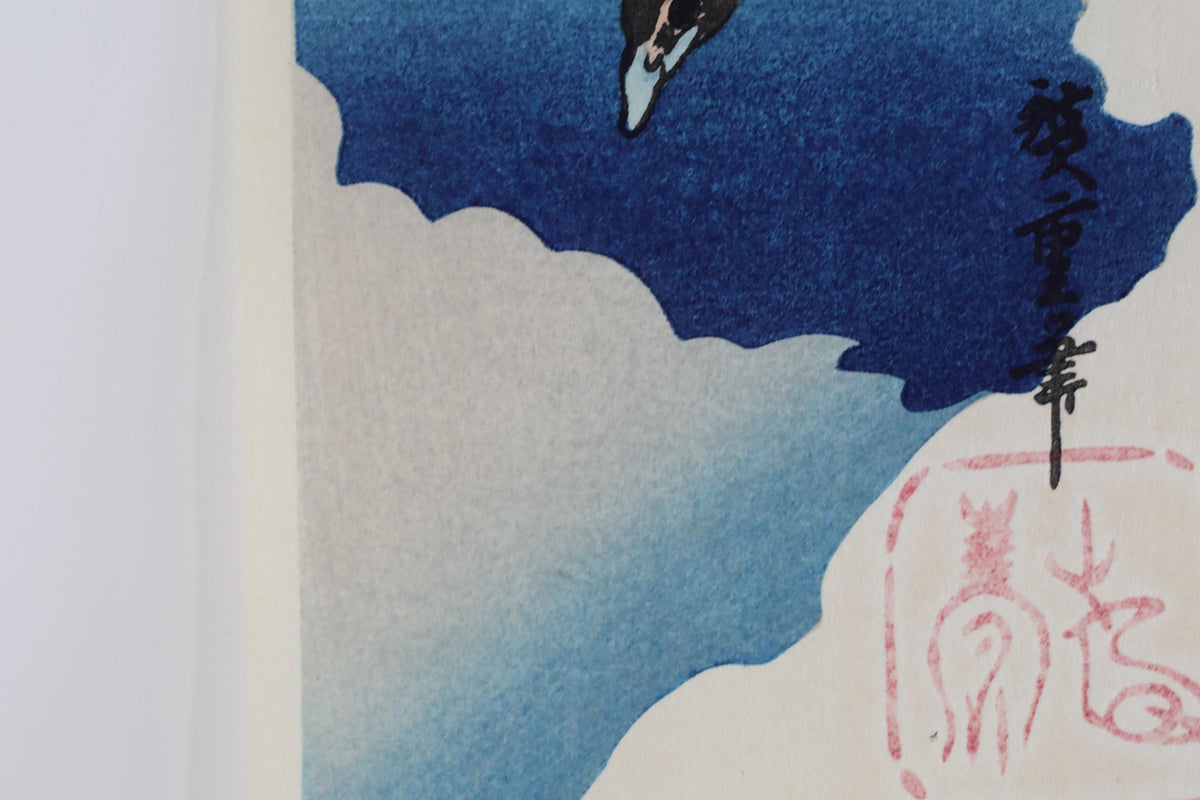 The image is a close-up of a blue and white abstract painting, featuring a bird and clouds. There is also a red and white symbol in the bottom right corner of the painting.