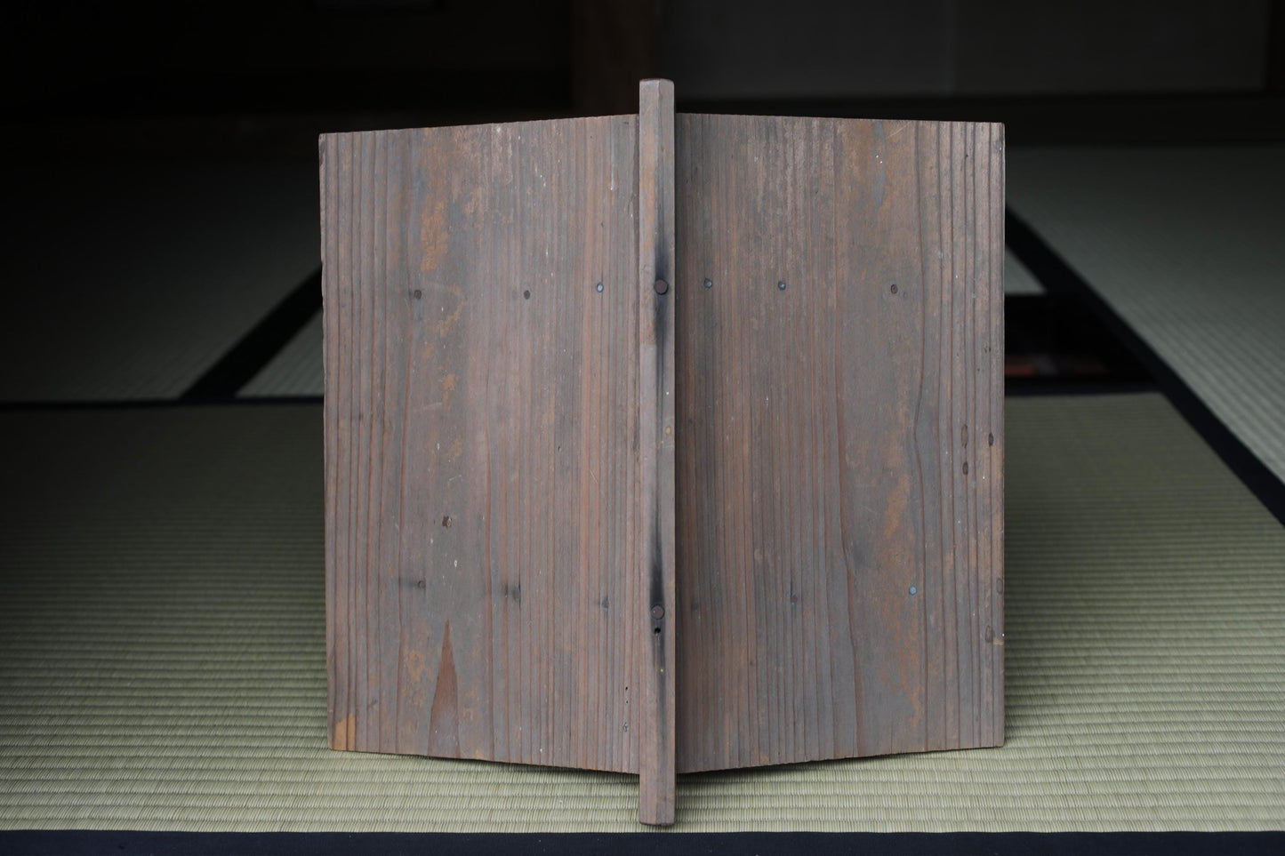 a wooden door or panel with a vertical line running through it, placed on a mat or mat-like surface.