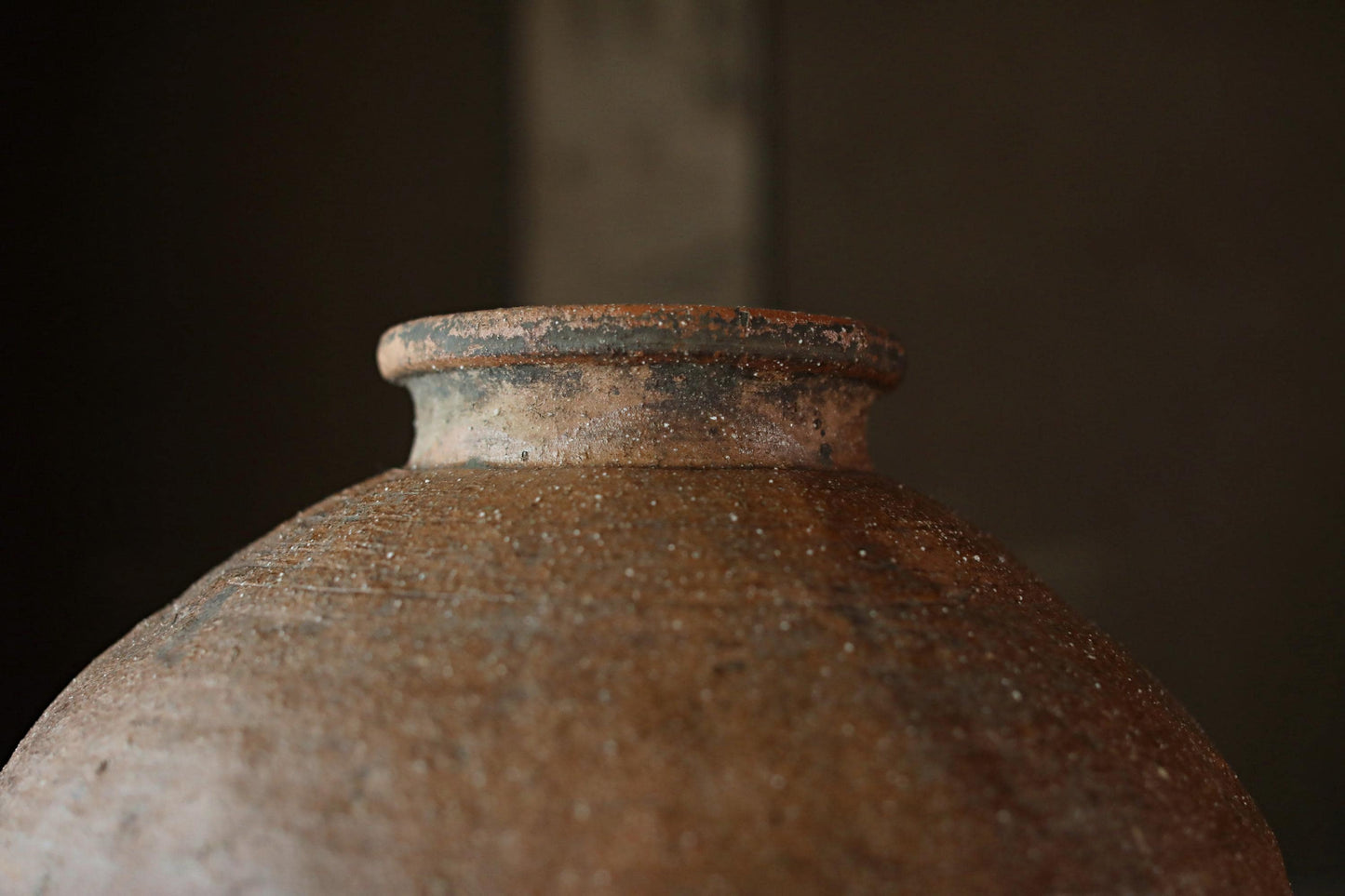A close-up view of an old, rusted clay pot with a weathered, textured surface.