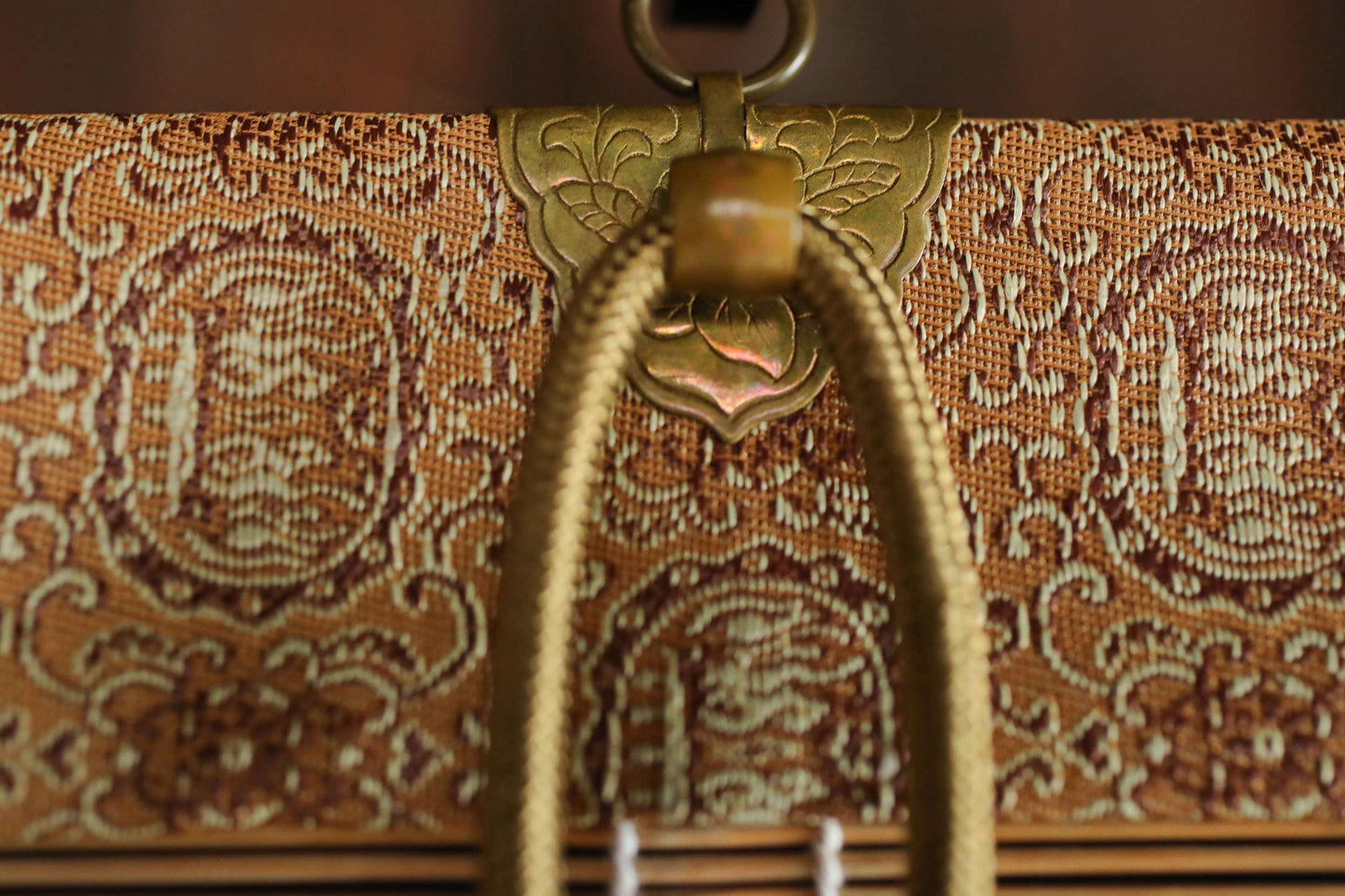 a close-up view of a decorative, ornate object with a gold-colored metal clasp and a woven rope handle.