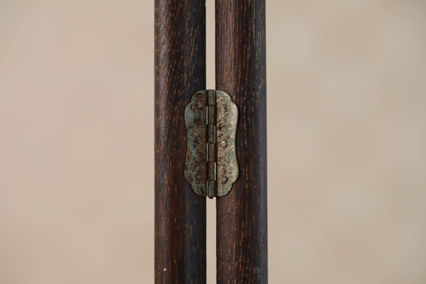 a close-up view of a wooden hinge with a metal plate attached to it, set against a plain background.