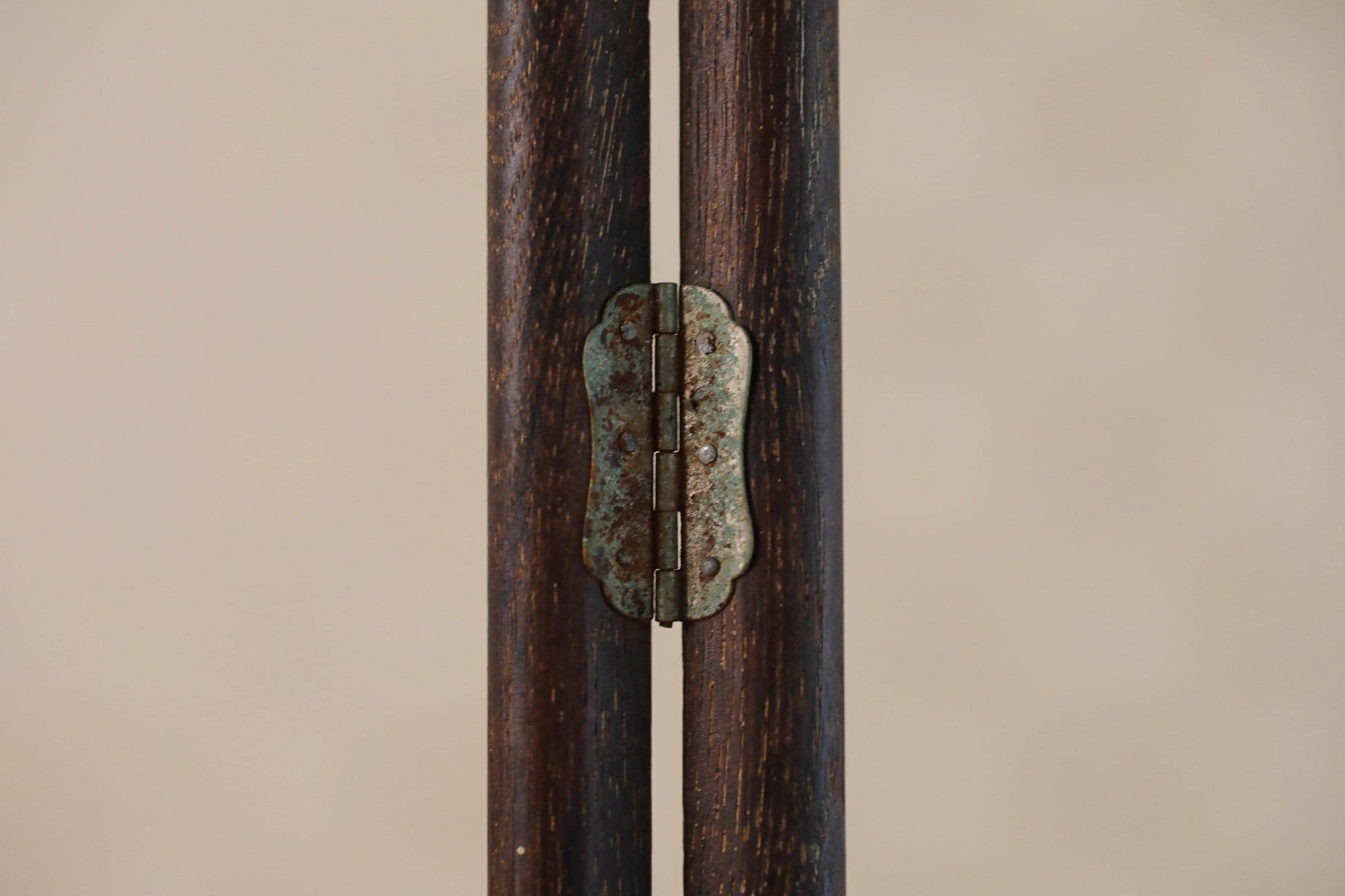 a close-up view of a wooden hinge with a metal plate attached to it, set against a plain background.