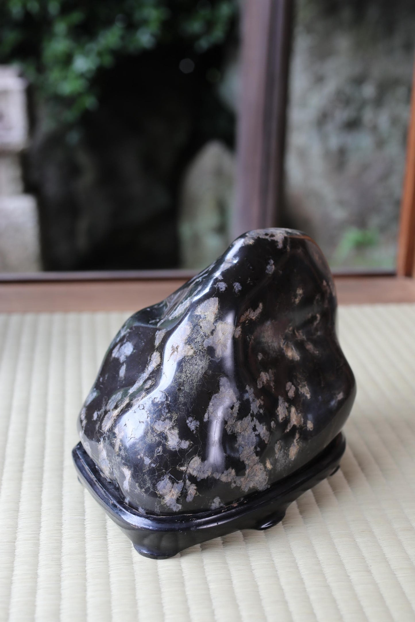 a black, speckled rock sitting on a white mat.