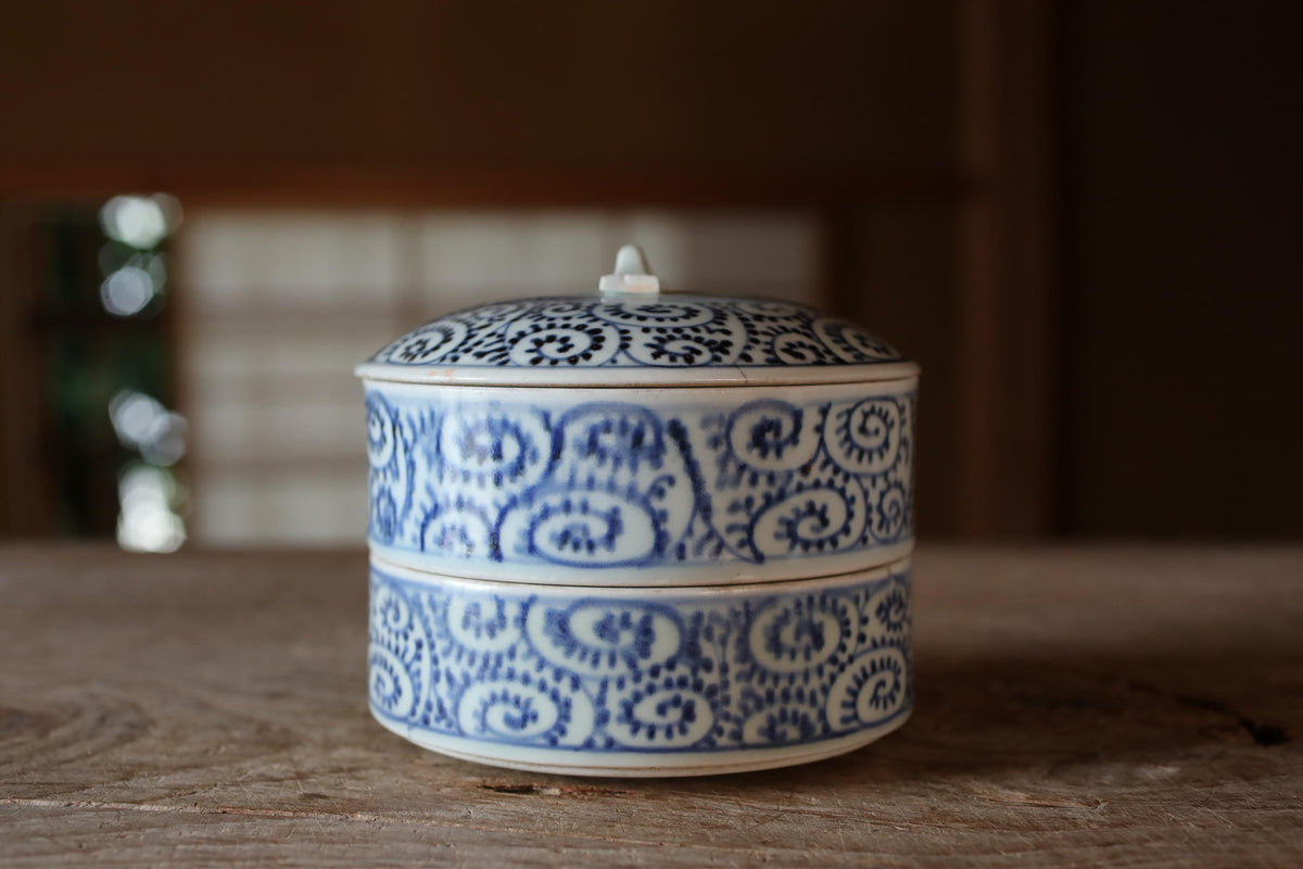 A decorative blue and white ceramic container with a lid sits on a wooden surface.