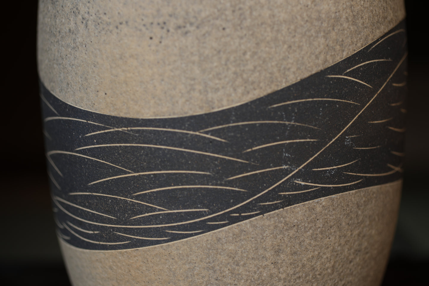 A close-up image of a ceramic vase with a black and white striped pattern on its surface.