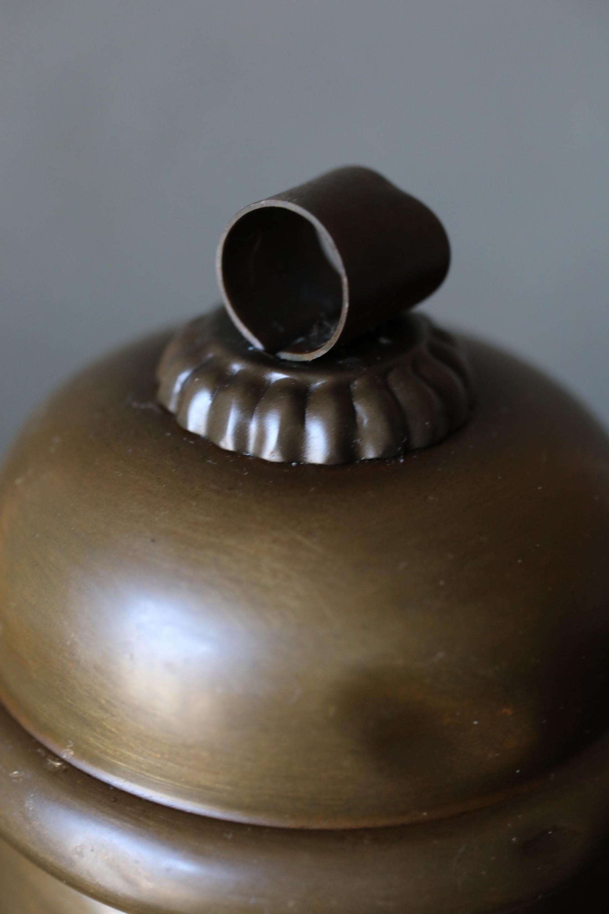 A close-up image of a brass-colored lampshade with a small metal piece on top.