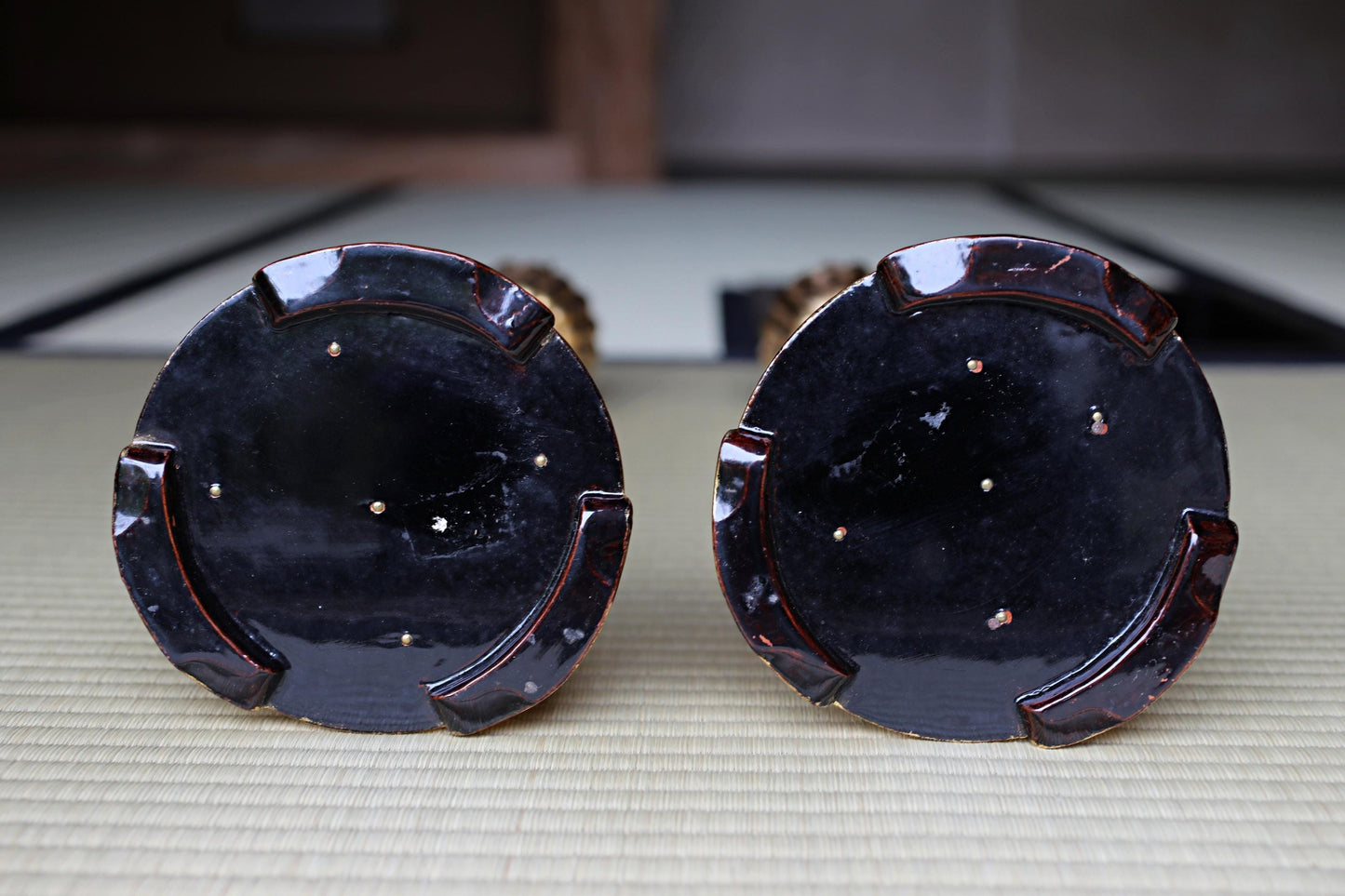 two dark-colored ceramic objects, possibly vases or bowls, placed side by side on a surface.