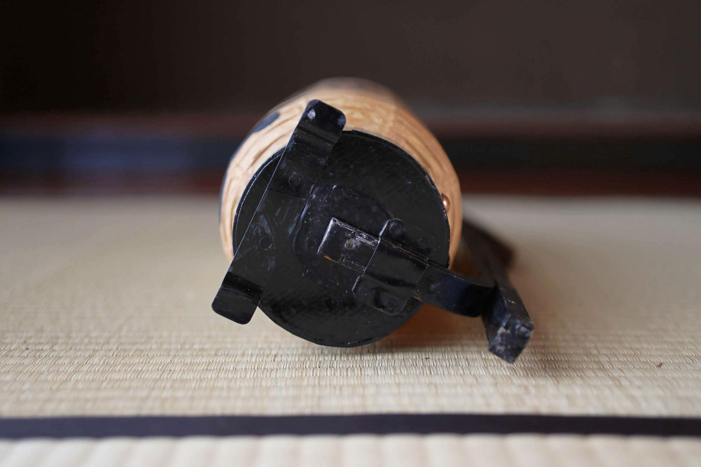 A close-up view of a wooden object with a black base, resting on a woven mat.