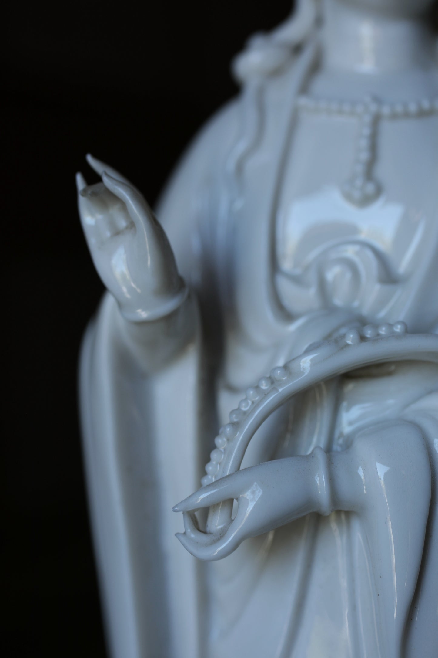 A close-up view of a white ceramic statue depicting a deity or religious figure, with intricate details and a serene expression.