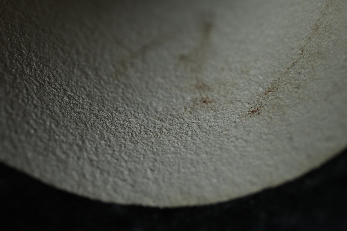 a close-up view of a textured surface, possibly a wall or a piece of furniture, with a dark background.