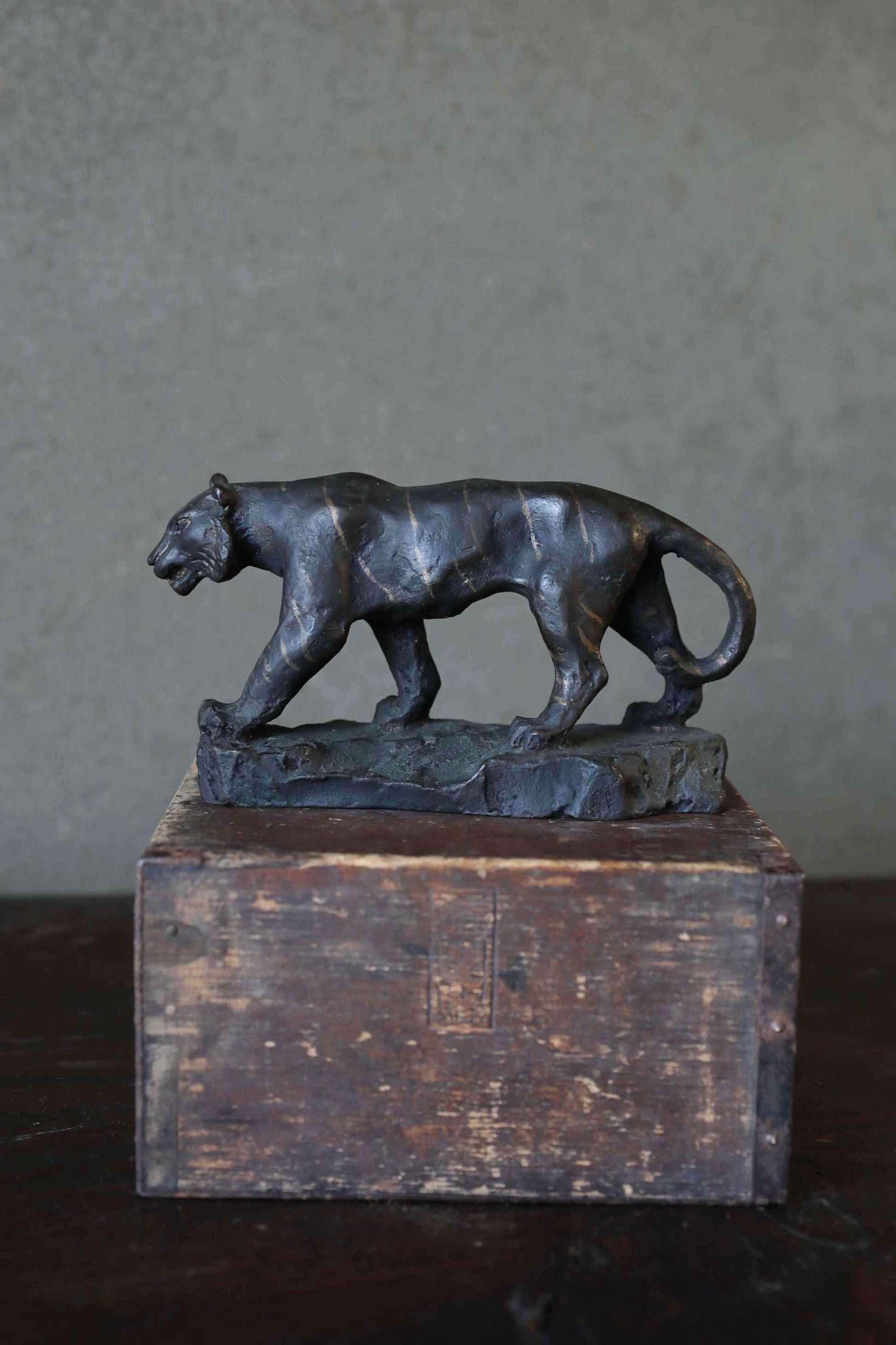 A bronze sculpture of a panther standing on a wooden box.