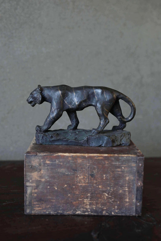 A bronze sculpture of a panther standing on a wooden box.