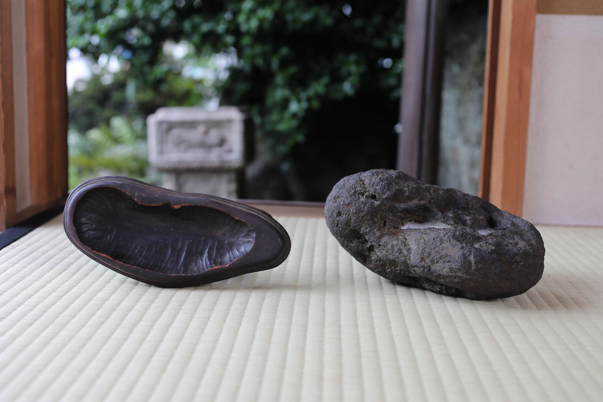 two rocks, one larger and one smaller, placed on a white surface.