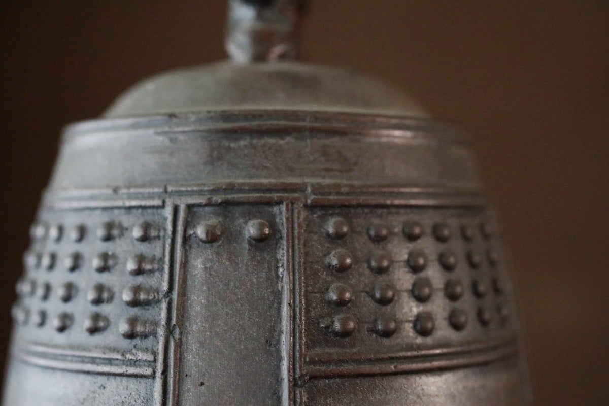A close-up view of a metal object with a textured surface, featuring a pattern of small circular dots or rivets.