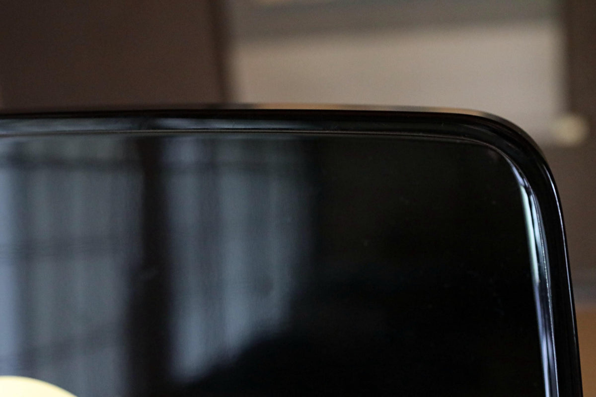 a close-up view of a black surface, possibly a screen or a piece of furniture, with a blurred background.