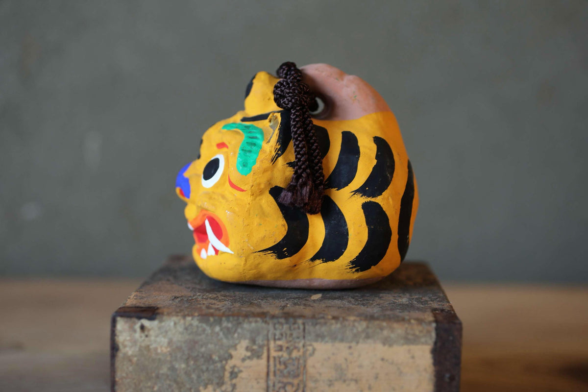A colorful, painted tiger figurine is displayed on a wooden surface.