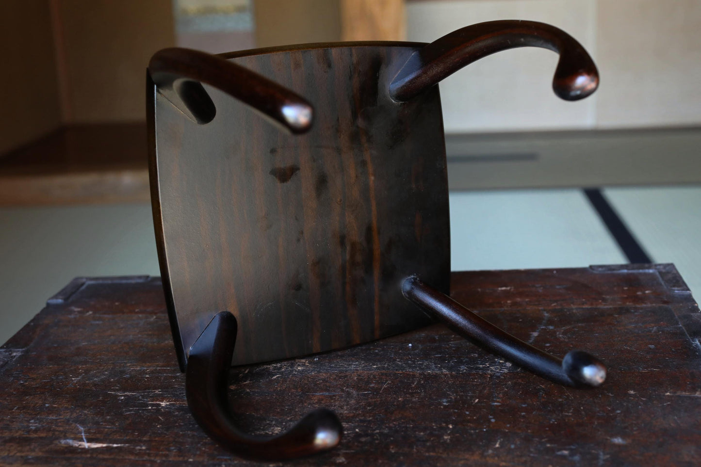 a wooden chair with a dark finish, sitting on a wooden surface.