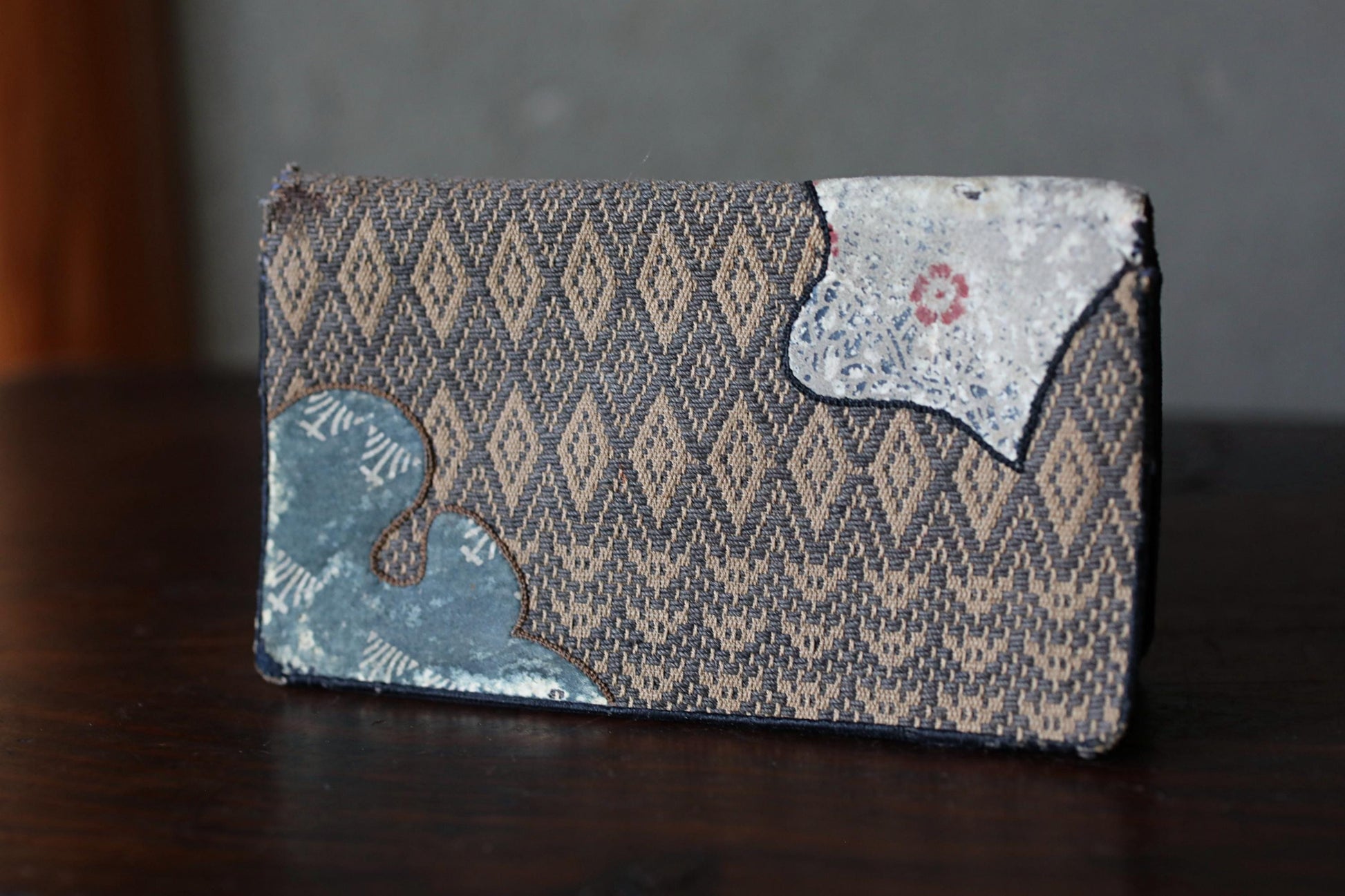 a wallet or card holder with a patterned design, sitting on a wooden surface.