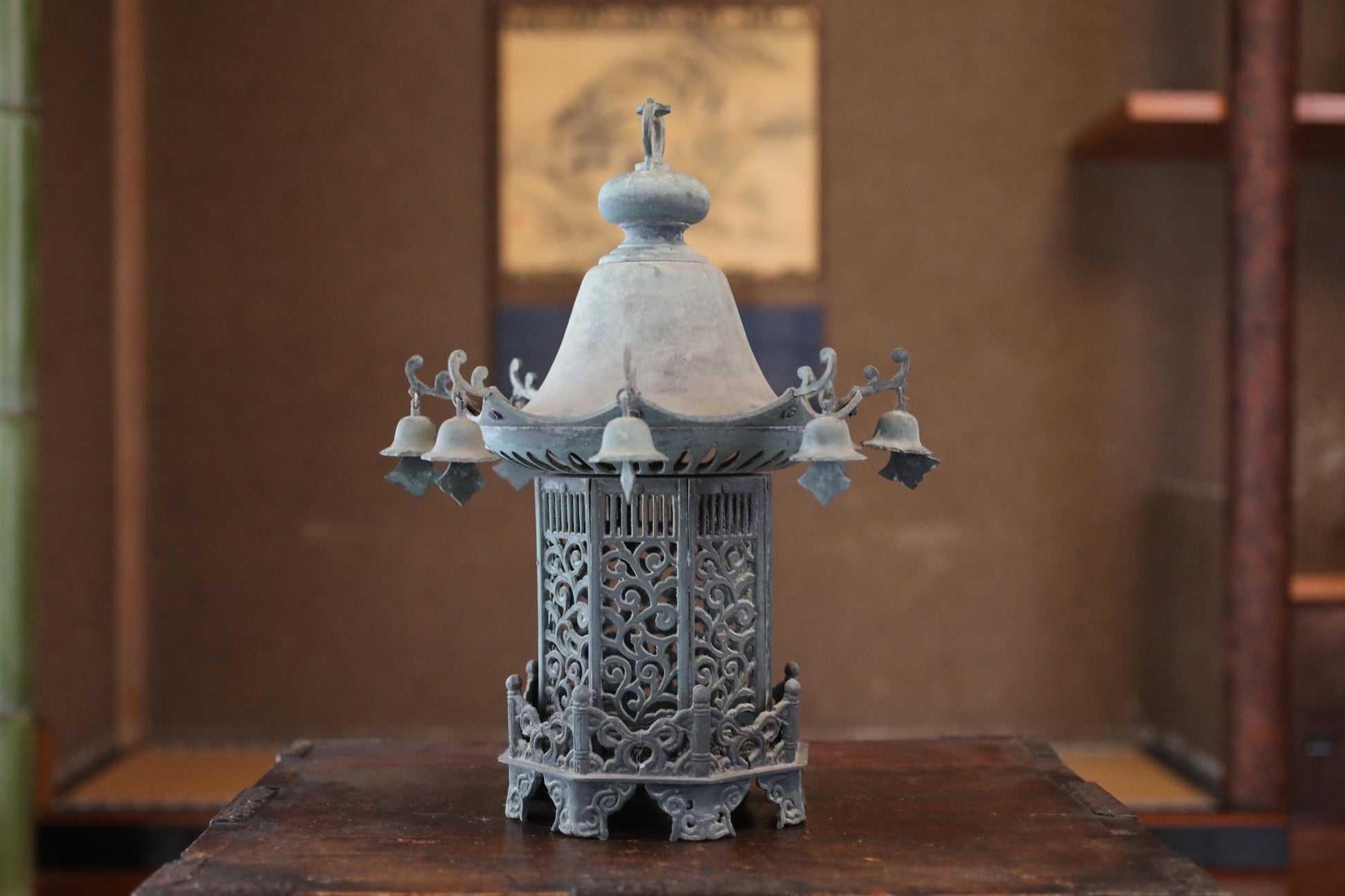 A decorative metal lantern with a domed top and bell-shaped elements, displayed on a wooden surface.