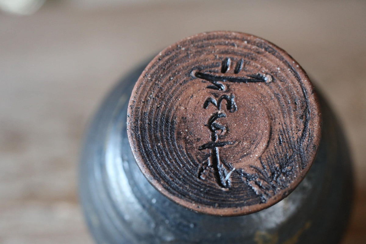 A close-up image of a ceramic object with a distinctive design on its surface, featuring a circular pattern and some text or symbol.