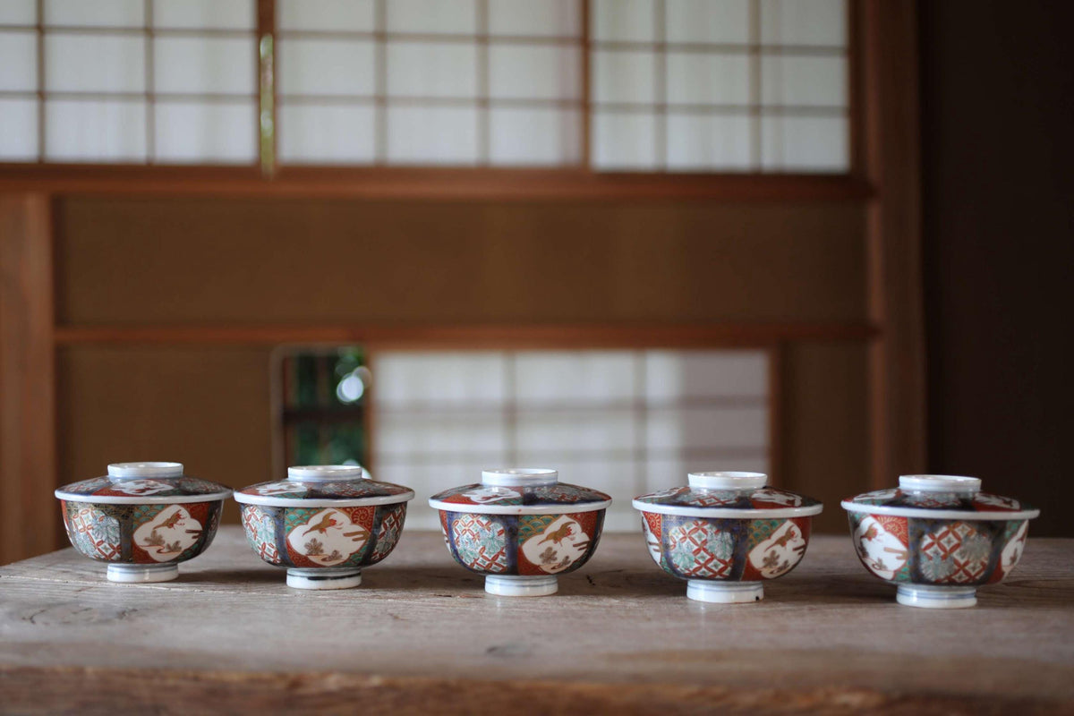 A row of five colorful ceramic bowls with intricate designs, arranged on a wooden surface.