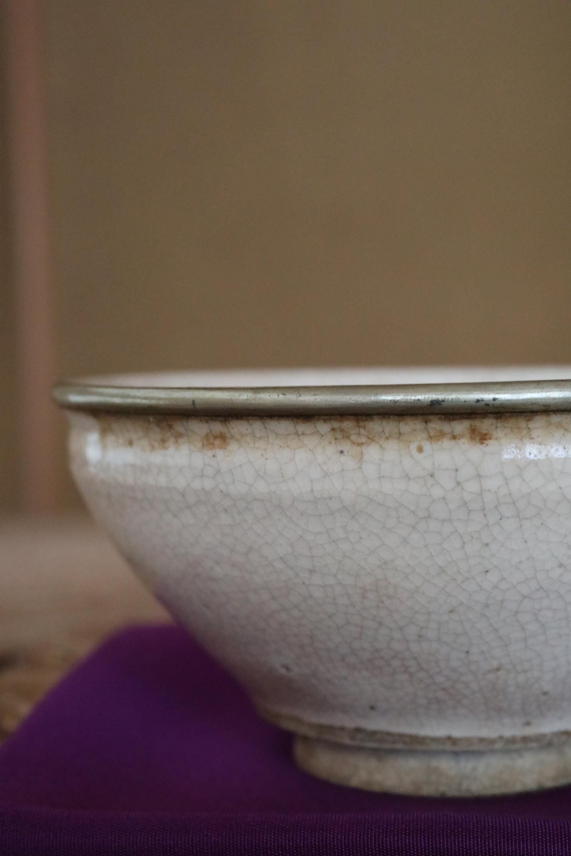 A close-up view of a white ceramic bowl with a textured surface, resting on a purple cloth.