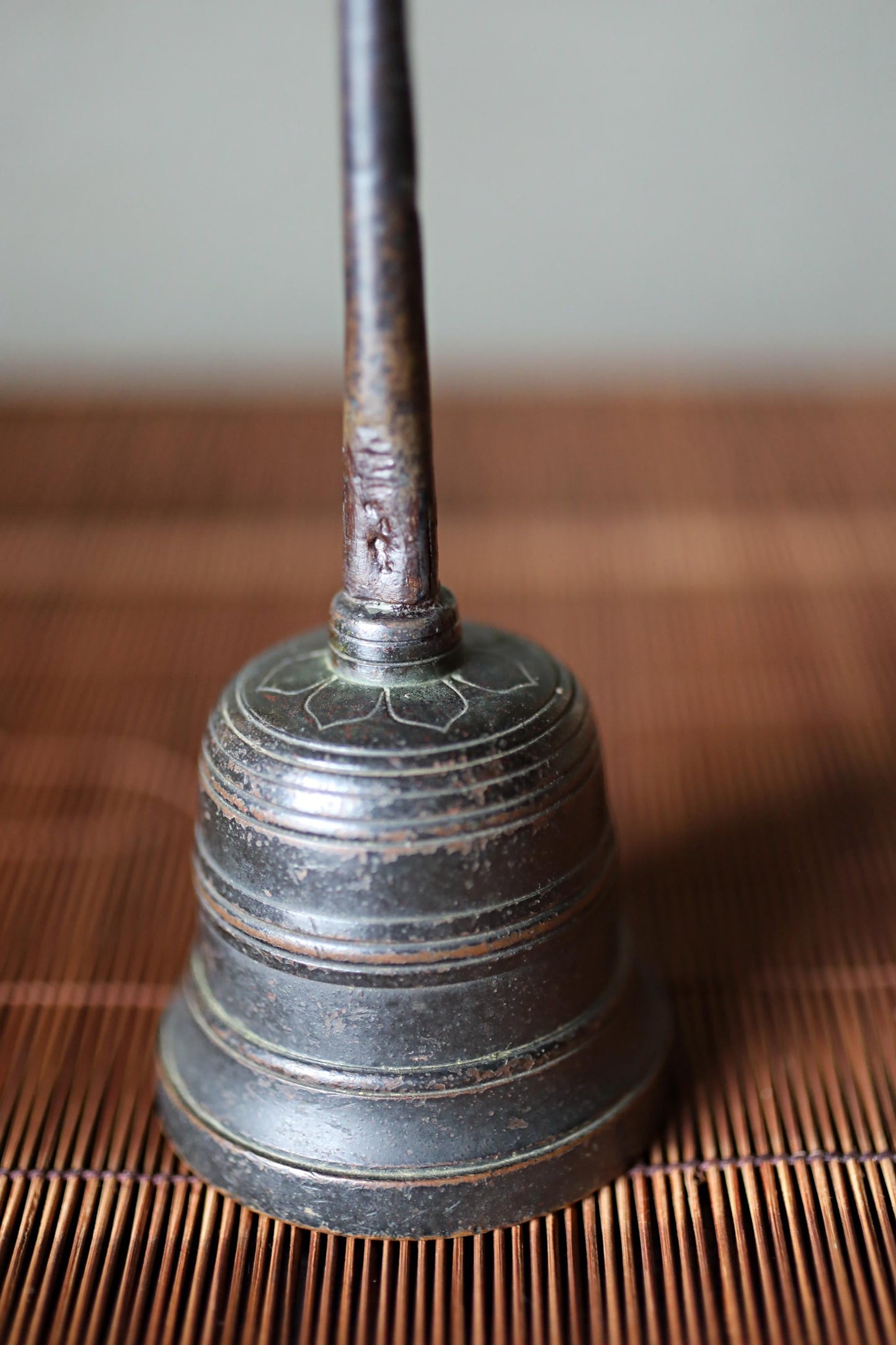 A close-up image of a metal bell with a rusted appearance, resting on a wooden surface.