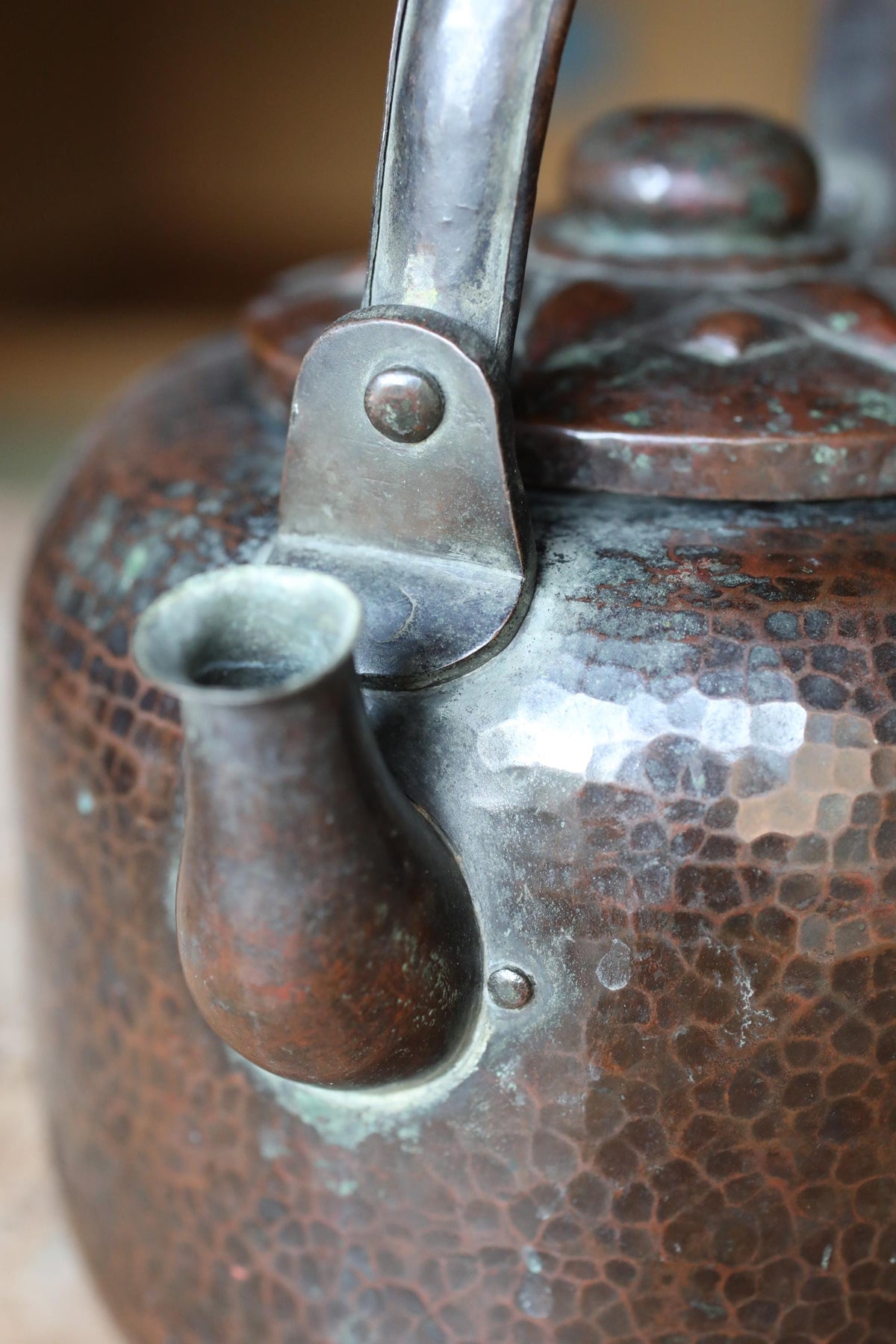 A close-up image of a metal teapot with a textured, weathered appearance.